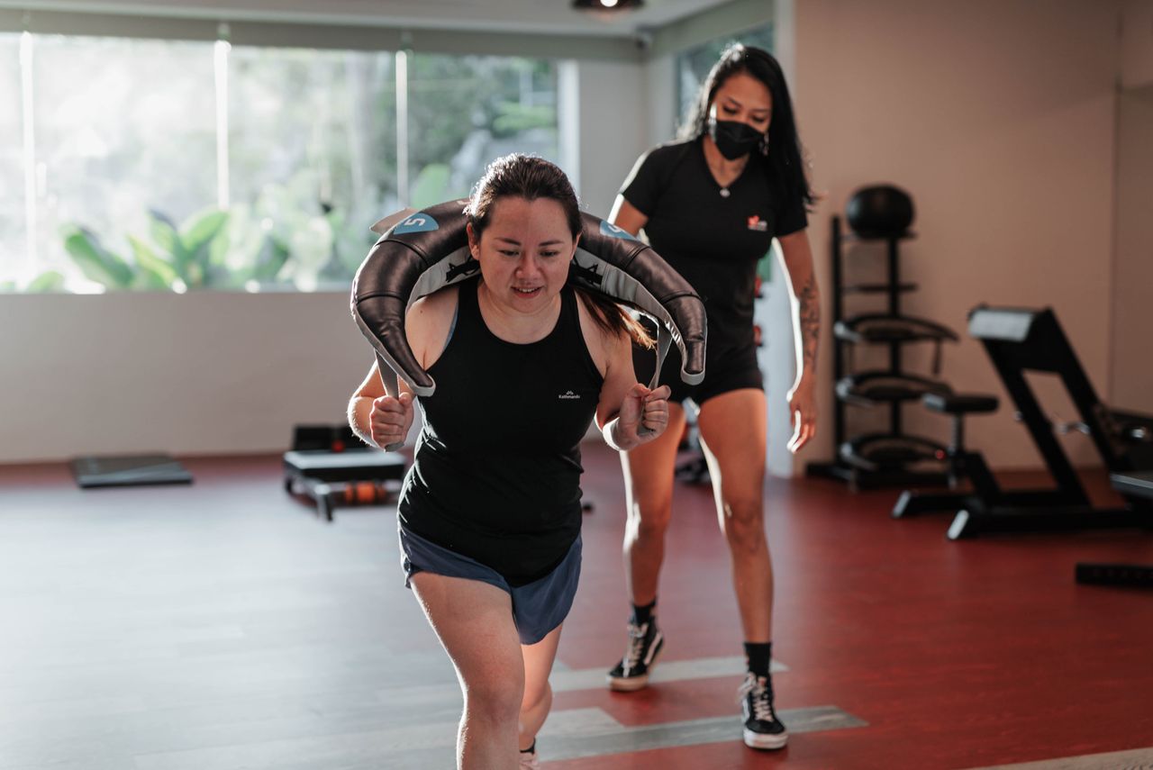 People working out with a trainer inside a bright gym.